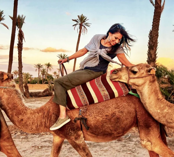 Solo female traveler riding a camel across the golden dunes of Merzouga Desert, showcasing the adventure of Solo Female Travel in Morocco.